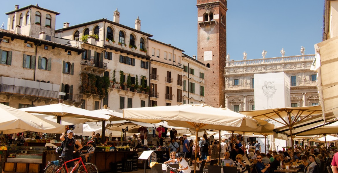 Piazza Della Erbe , the main market square in the city of Verona in Italy, filled with market stalls and terraces of cafés and restaurants