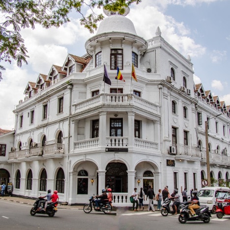 White colonial building in the city center of Kandy in Sri Lanka with tuk-tuks passing by.