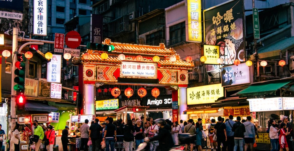 Many people and neon lights at Raohe street night market in Taipei Taiwan